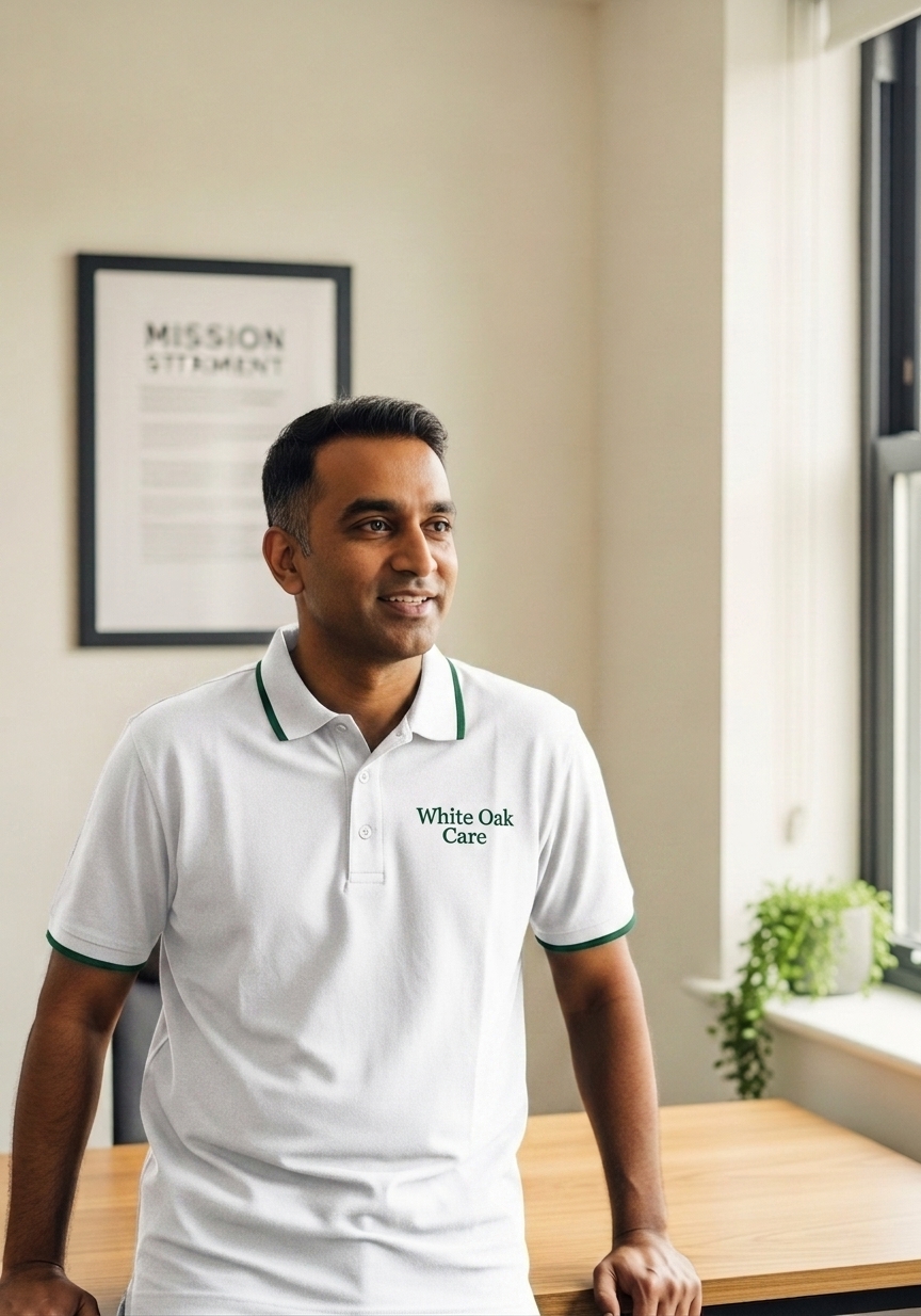 The founder of White Oak Care in a branded teal uniform standing in a modern UK office.