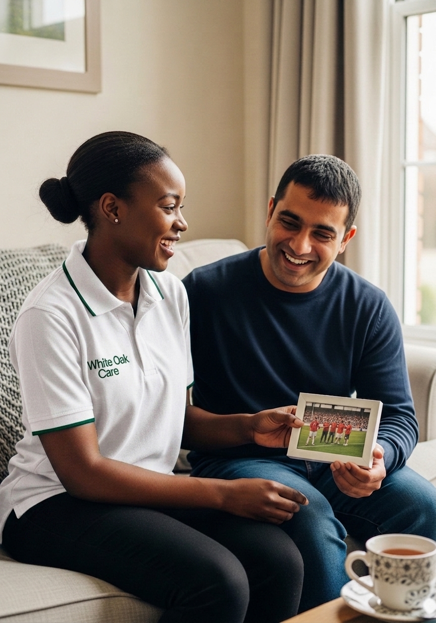 A White Oak Care support worker and a resident with a learning disability laughing together as they look at a photograph from a football match.