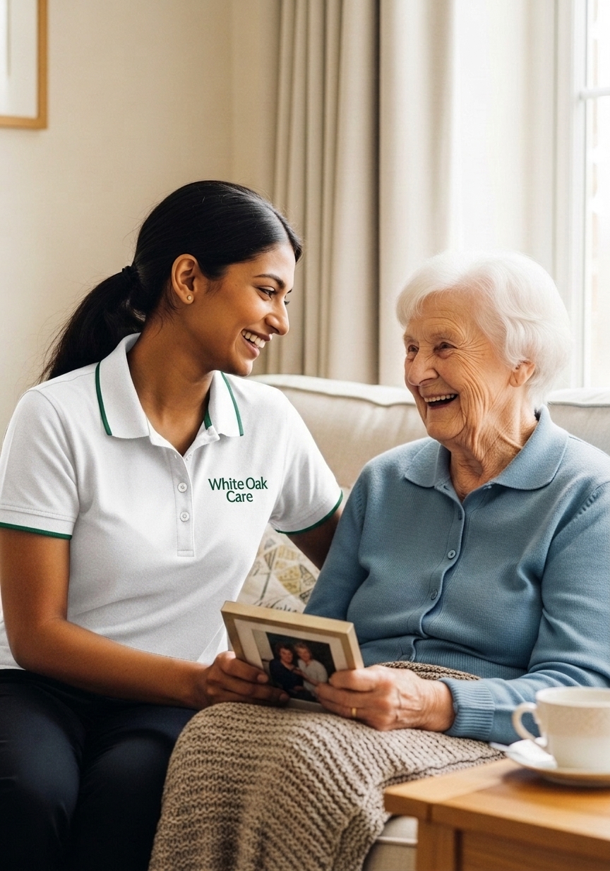 A White Oak Care support worker laughing with a resident as she shares a family photograph on the sofa of a supported living home.